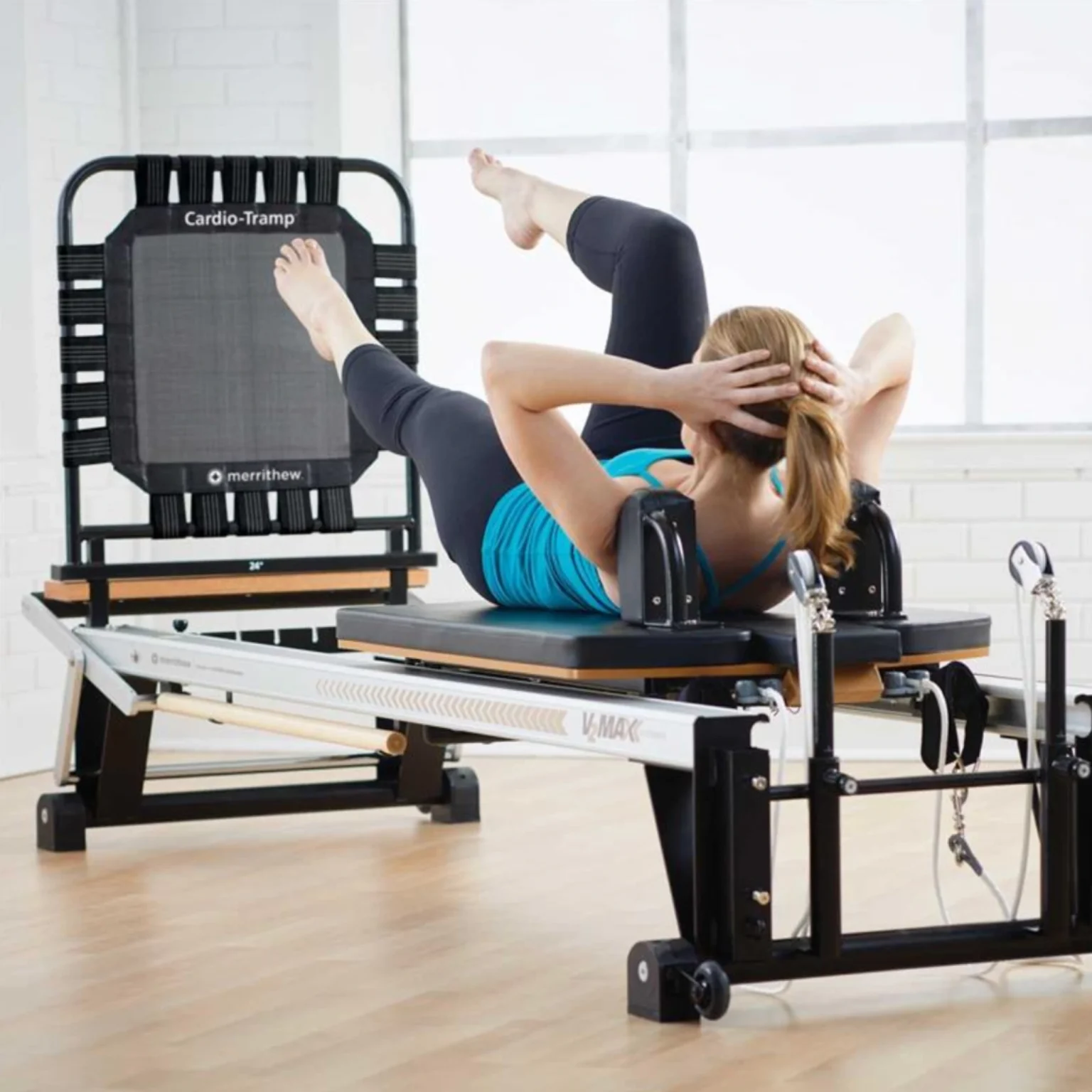 A person in the UAE engaging in a rebounding exercise on the Merrithew Cardio-Tramp® attached to a Rehab V2 Max Reformer, demonstrating its suitability for various fitness levels and rehabilitation purposes.